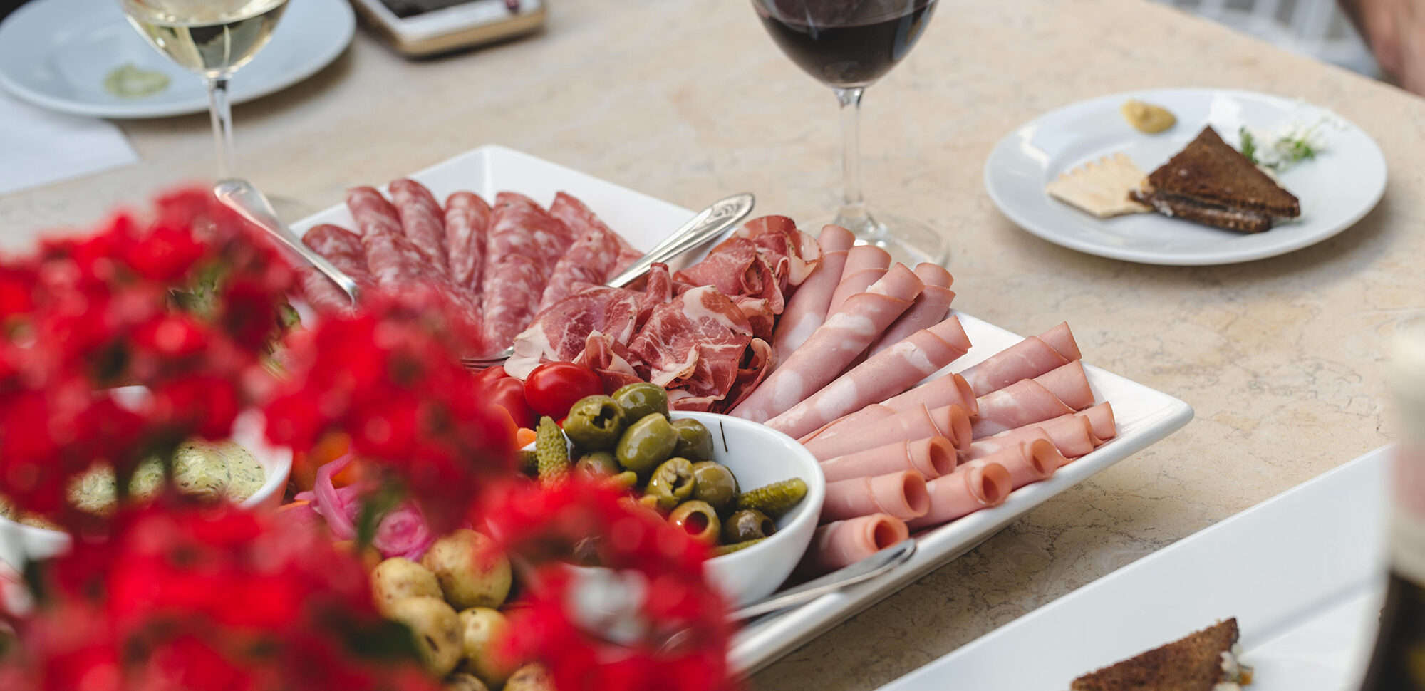 A yummy meat and cheese tray with wine and flowers